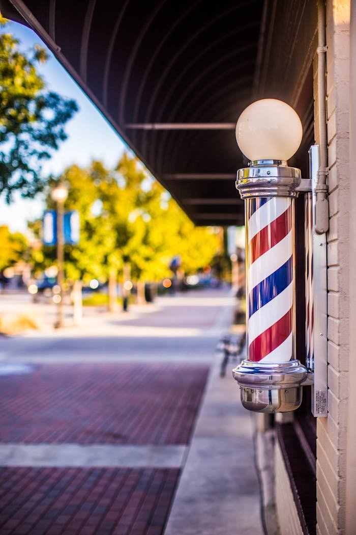 our-journey-03 Classic barber pole on a vibrant city street under a sunny sky.